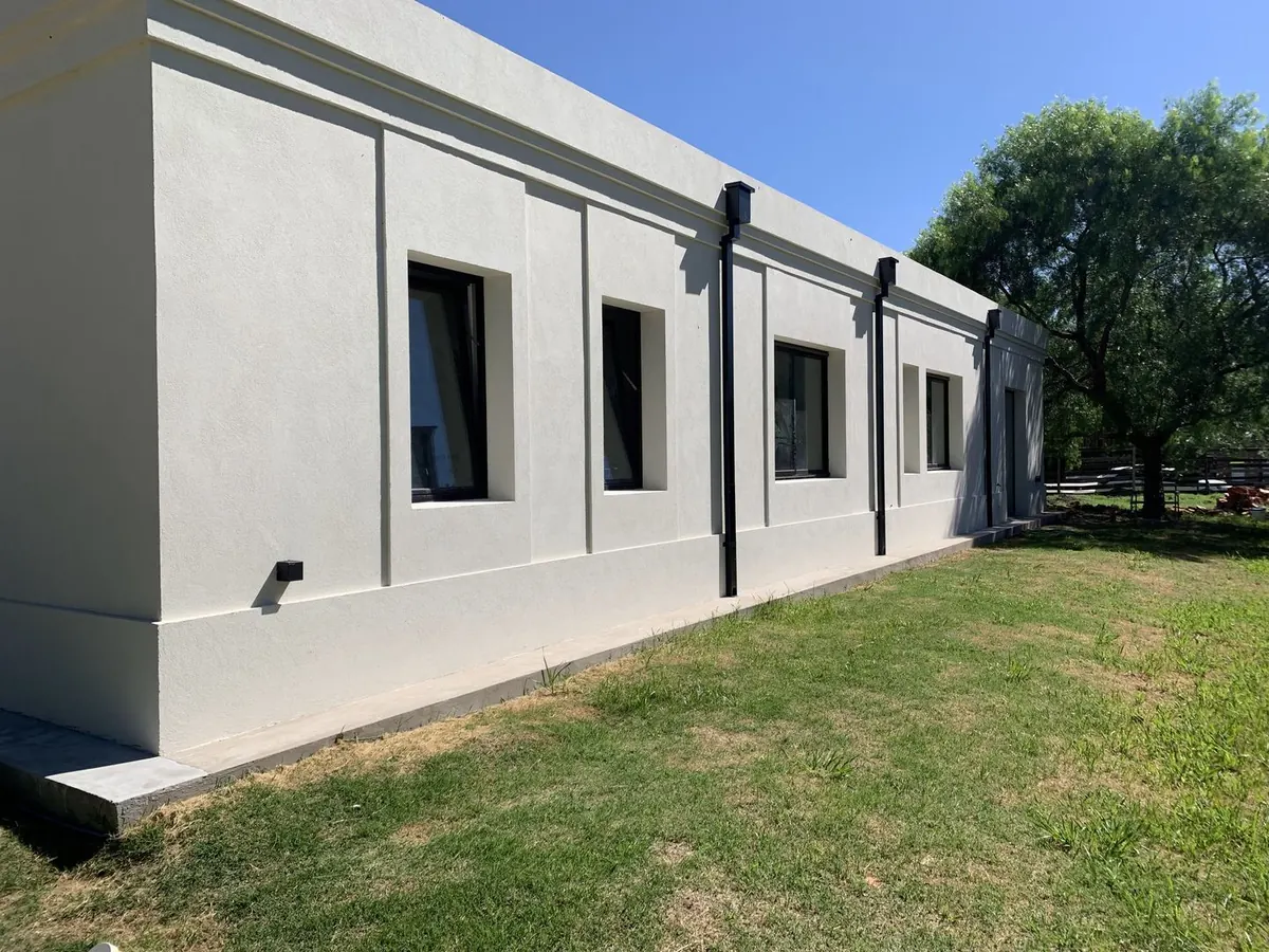 Lateral de la casa con molduras en el revoque y ventanas de marco negro